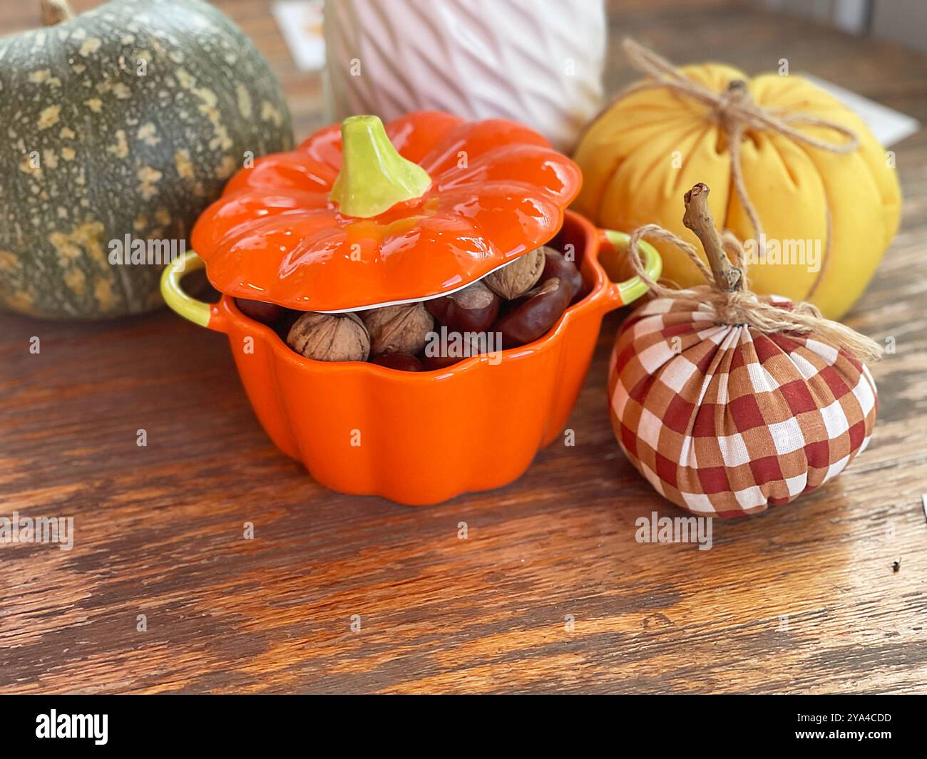 Pentola di noci, castagne e zucche su un vecchio tavolo di legno. Composizione per le vacanze di Halloween. Autunno e raccolto. Foto Stock