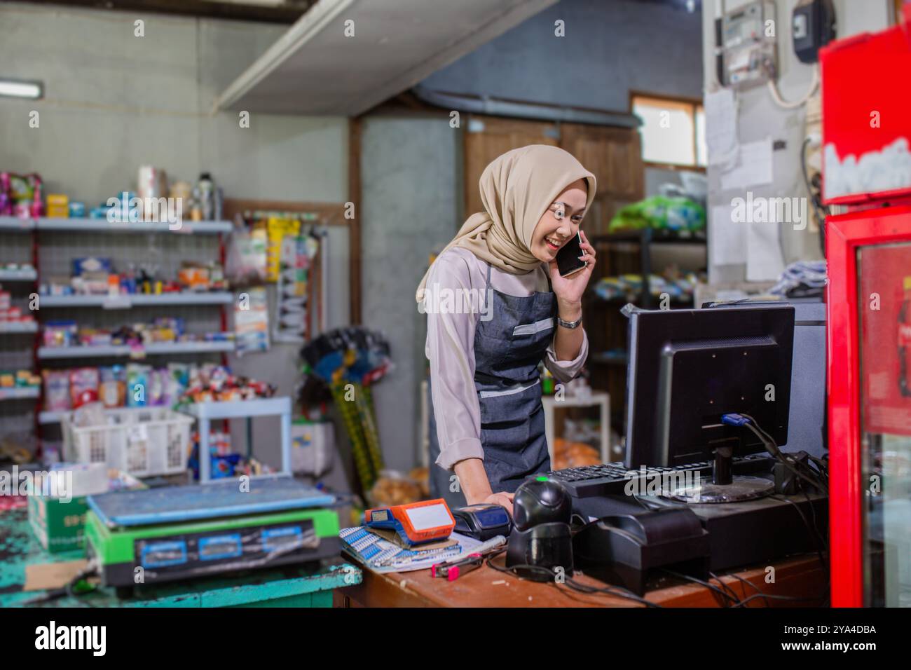 Un imprenditore impegnato gestisce il proprio negozio con un telefono, bilanciando più attività Foto Stock