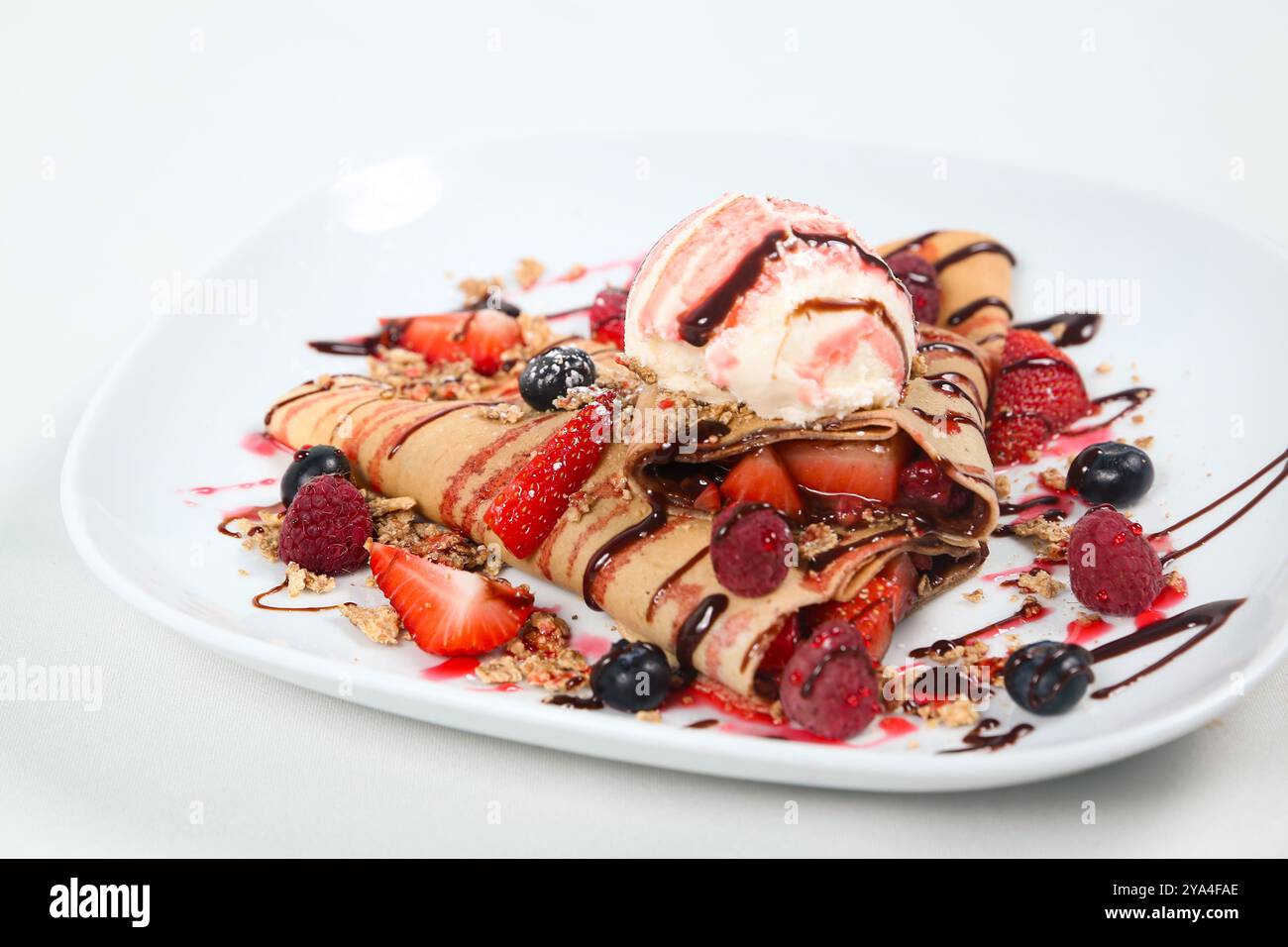 Gelato fresco in Crêpe decorato con bacche miste e sciroppo al cioccolato Foto Stock