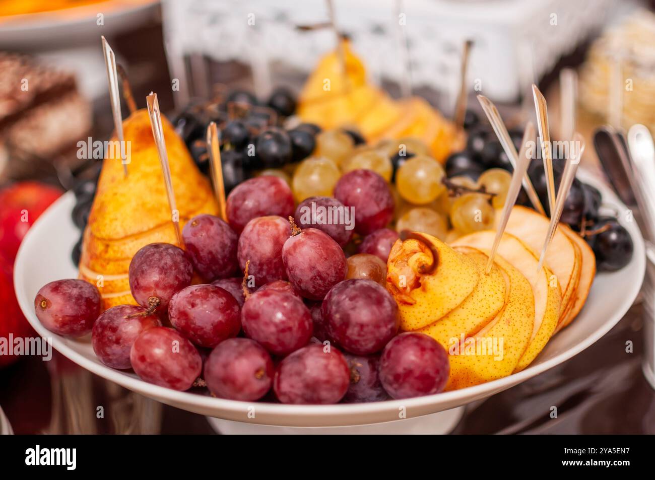 Un vivace e fresco vassoio di frutta che mostra una serie di variopinte uve e pere. Foto Stock
