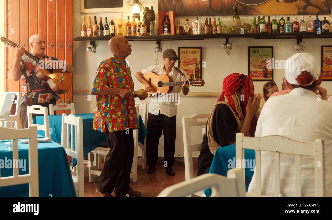 L'Avana, Cuba - 1° aprile 2024: Gruppo di musicisti buskers in un paladar, ristorante bar cubano di proprietà privata, che esegue musica dal vivo per i clienti che mangiano. Foto Stock