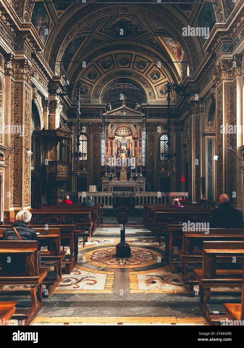 L'interno ornato di una chiesa cattolica a Monza, in Italia, presenta intricati dettagli dorati, soffitti ad arco e un altare illuminato. Foto Stock