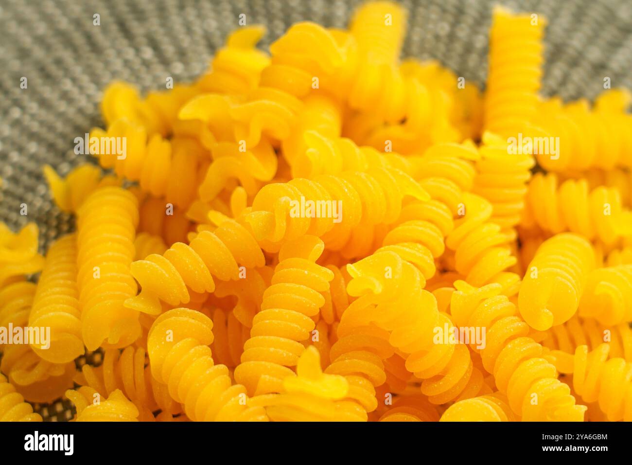 Pasta biologica gialla italiana su un panno di vimini ecologico. Primo piano con maccheroni crudi Foto Stock