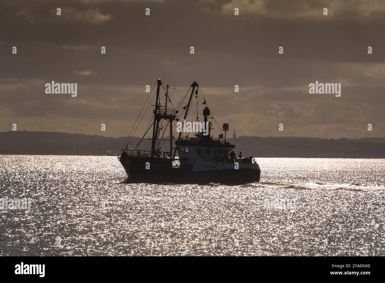 Sagoma di un peschereccio da traino che lascia il porto Foto Stock