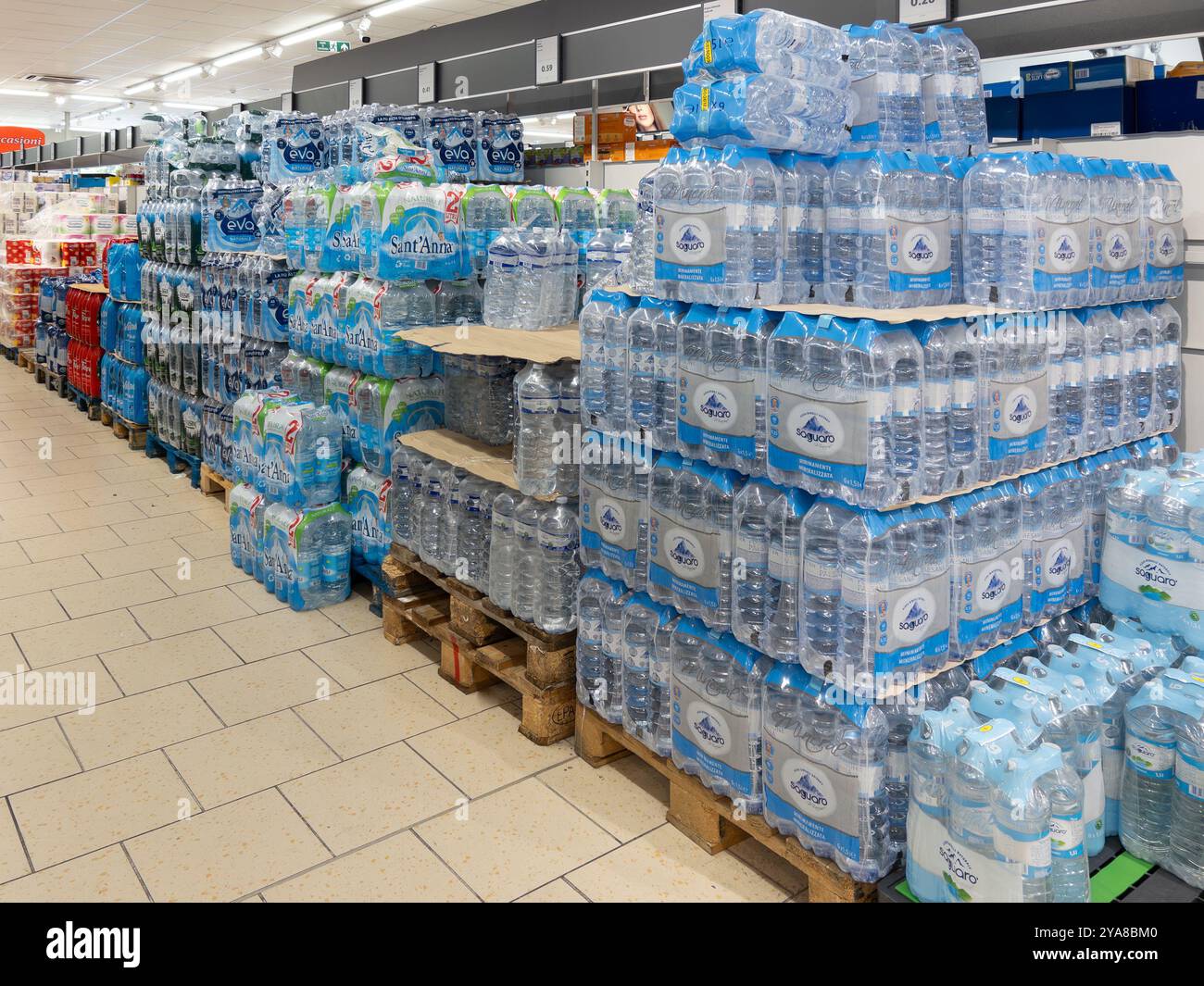 Italia - 12 ottobre 2024: Acqua in bottiglie di plastica di varie marche in confezioni impilate su pallet esposte nella corsia dei supermercati italiani Foto Stock