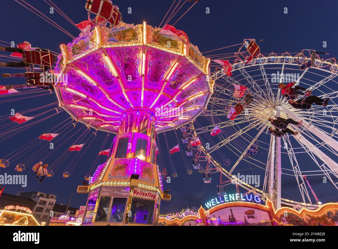 Giostra illuminata e ruota panoramica di notte in un vivace parco divertimenti, parco divertimenti, volo a onde, Cannstadter Volksfest, Stoccarda-Bad Cannstsdt, Baden Foto Stock