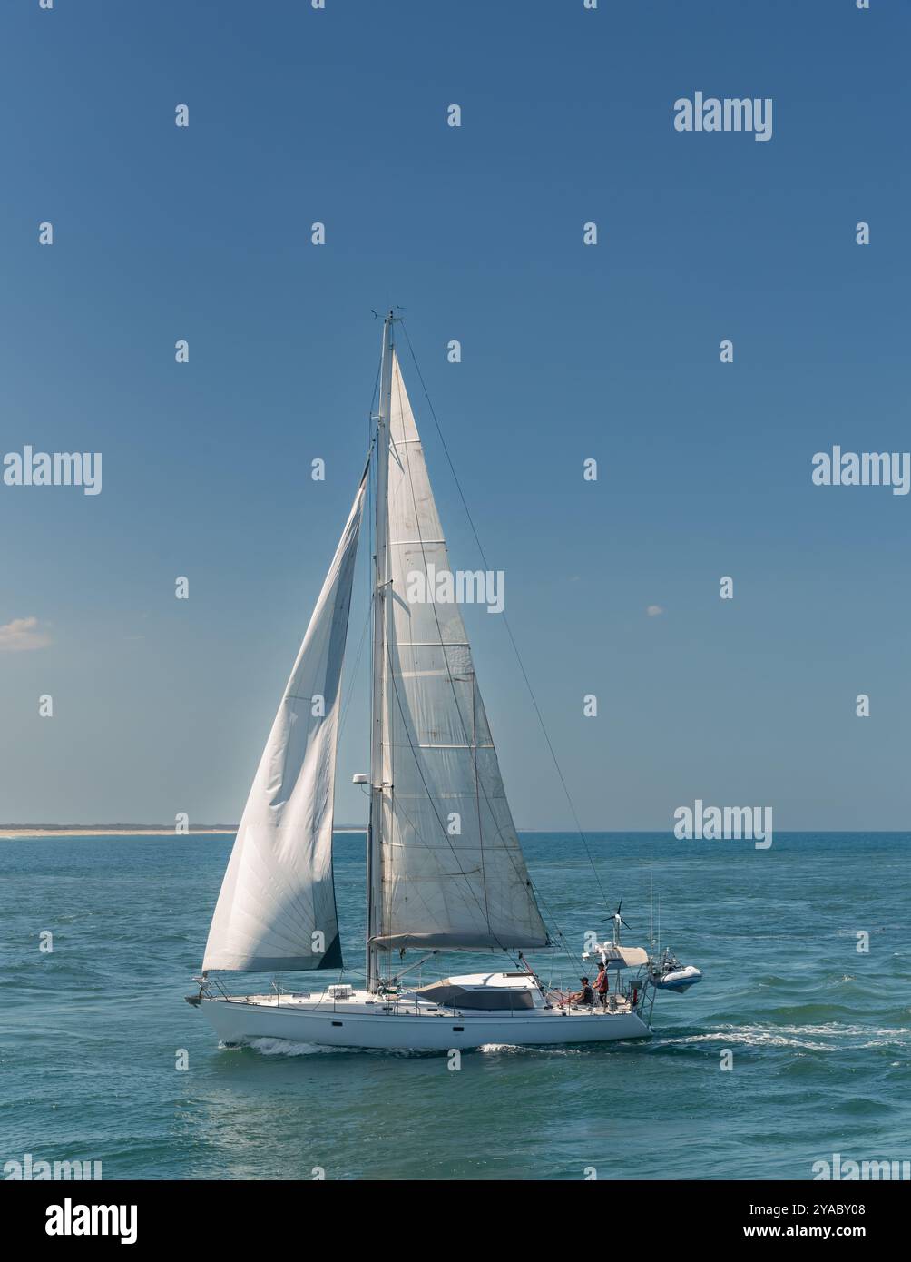 Yacht a vela bianco in acque calme e un cielo azzurro cristallino. Foto Stock