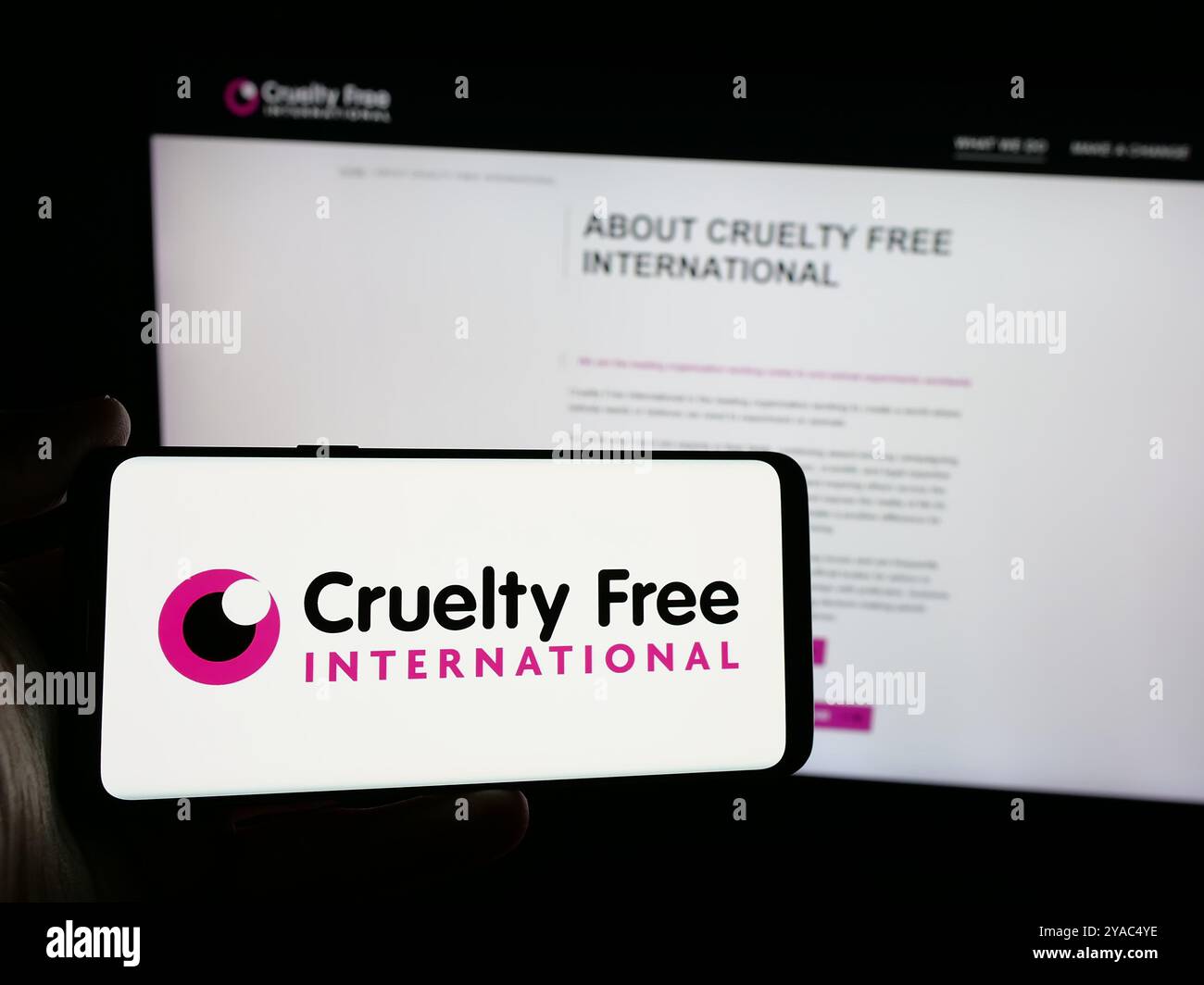 Persona con smartphone con logo dell'organizzazione Cruelty Free International sullo schermo di fronte al sito Web. Mettere a fuoco il display del telefono. Foto Stock