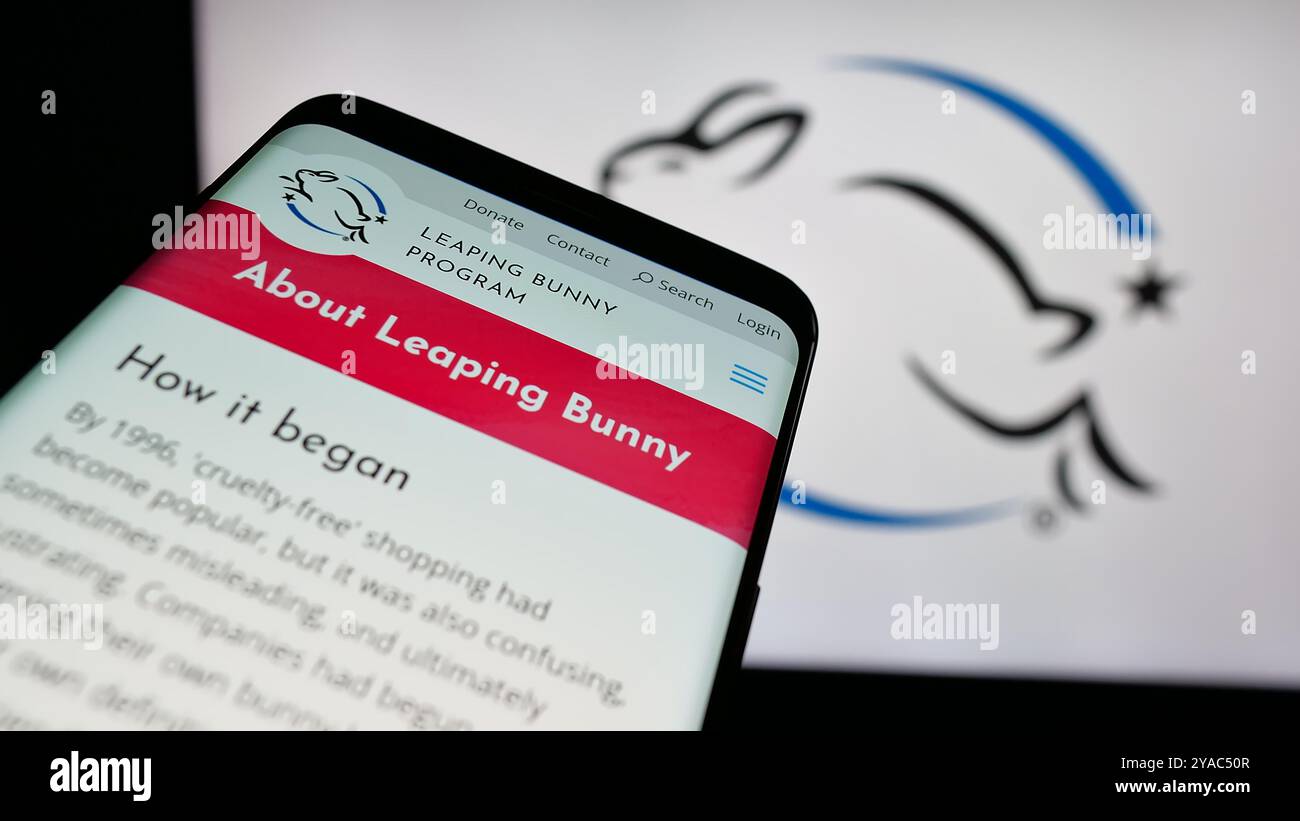 Smartphone con sito Web dell'organizzazione di certificazione Leaping Bunny Program sullo schermo davanti al logo. Mettere a fuoco in alto a sinistra sul display del telefono. Foto Stock