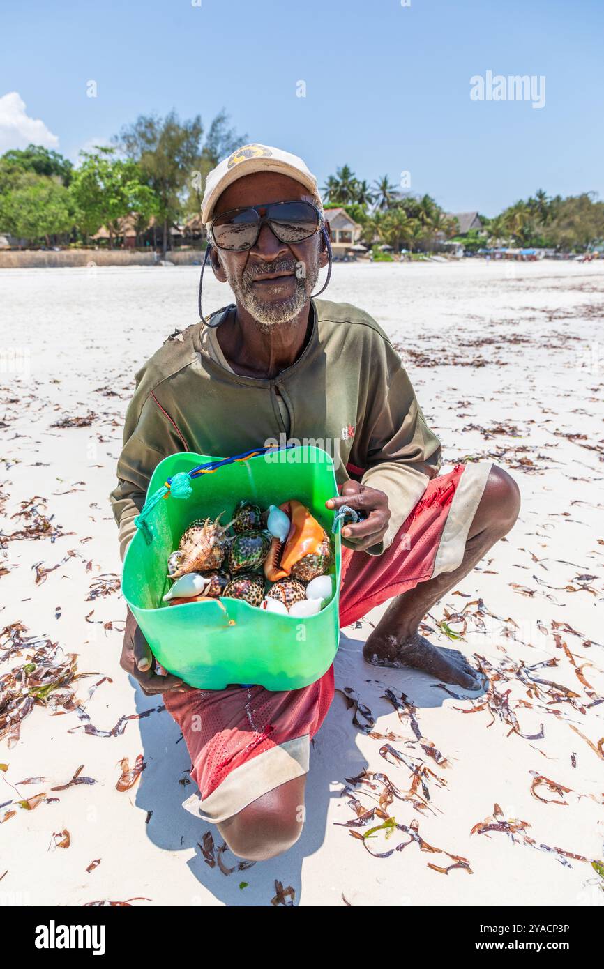 Uomo del posto che vende conchiglie di mare a Diani Beach, nell'Oceano Indiano, nel distretto di Galu, Mombasa, nel Kenya meridionale, Foto Stock