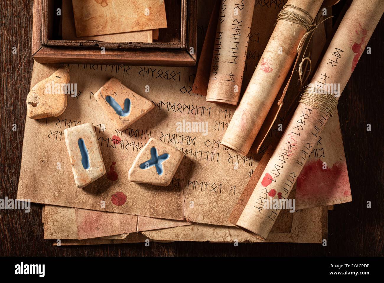 Primo piano di antiche pietre di rune di futhark, manoscritti antichi e rotoli come sfondo mistico Foto Stock