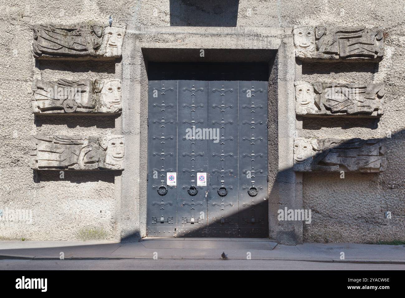 Una serie di curiosi bassorilievi su una porta a Clemens-Holzmeister-Stiege vicino all'ingresso del Toscaninhof, Altstadt Salisburgo, Austria. Foto Stock