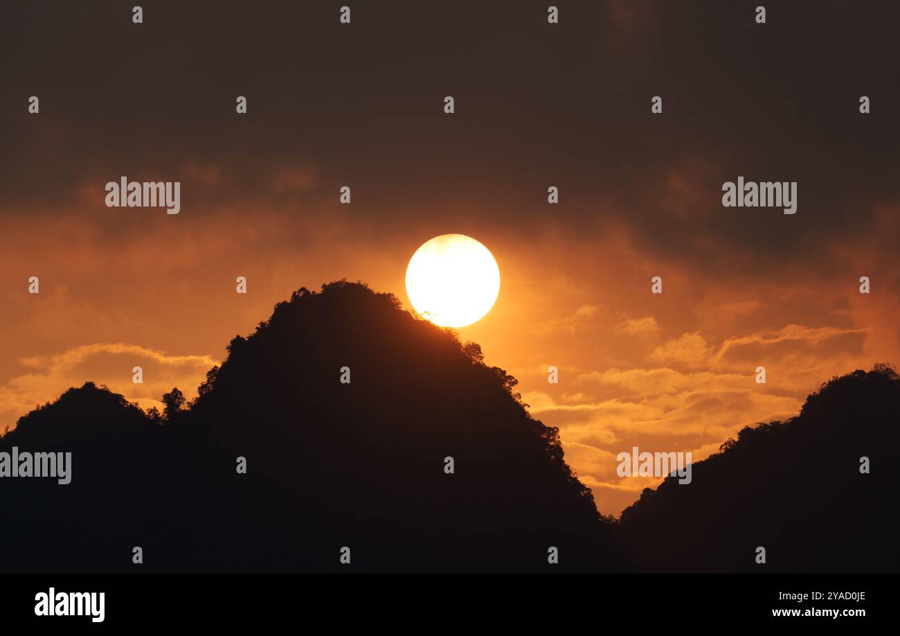 Splendido tramonto vivace con cielo arancione sopra la silhouette di montagna Foto Stock