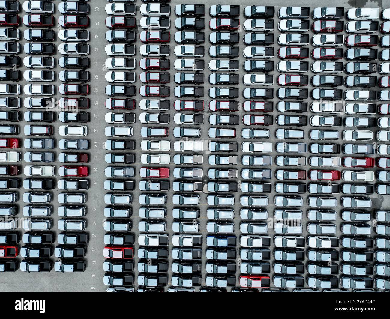 Vista dall'alto, parcheggio dello stabilimento di assemblaggio di veicoli con auto, pick-up e SUV. Logistica, strategia di trasporto, elettrica e ibrida Foto Stock