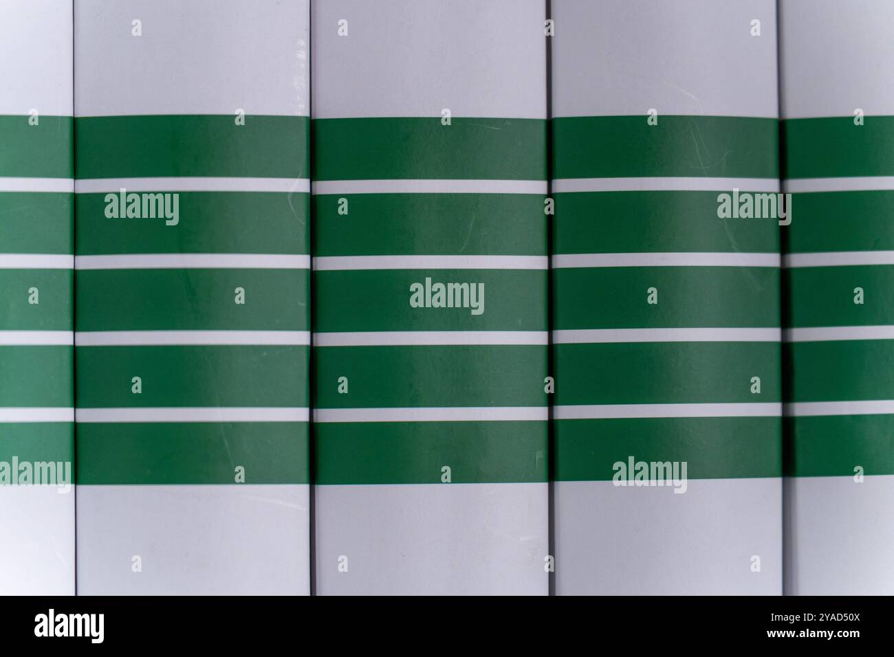 Simmetria e ritmo: Copertine di libri verdi e bianchi in un'impostazione Libreria Foto Stock