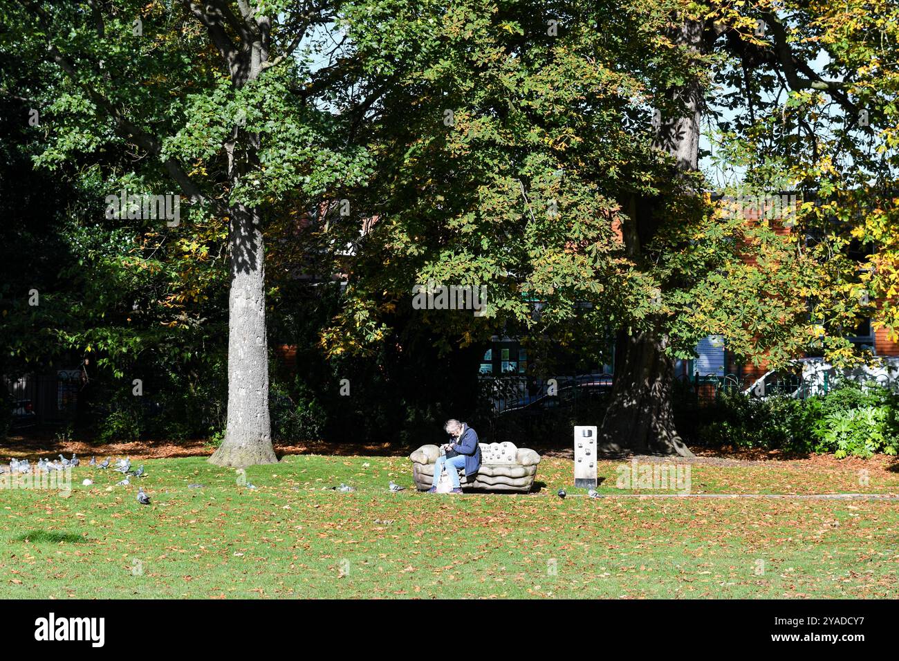pensionato seduto su una panchina del parco delle regine di loughborough Foto Stock