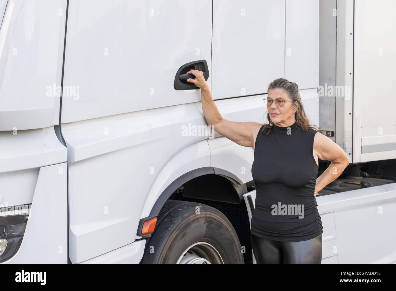 Un attraente conducente anziano al suo veicolo Foto Stock