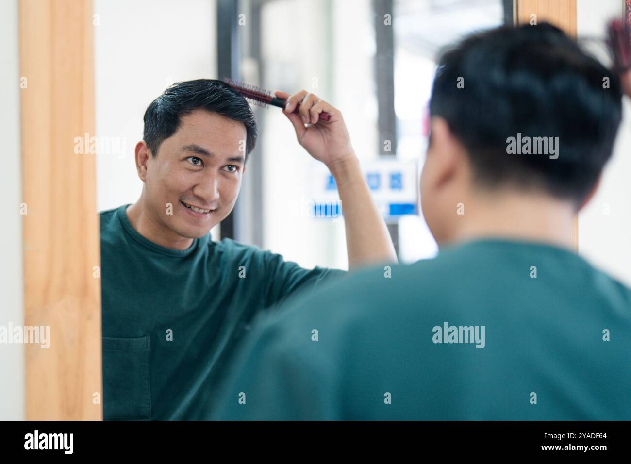 Un uomo si sta lavando i capelli davanti a un grande specchio Foto Stock