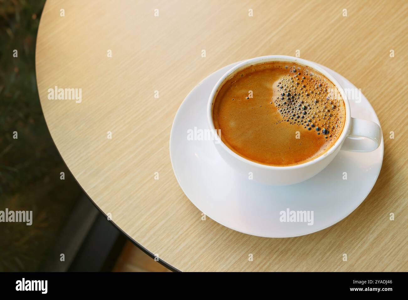 Tazza di caffè caldo con superficie ghiacciata isolata su un Tavola rotonda in legno Foto Stock