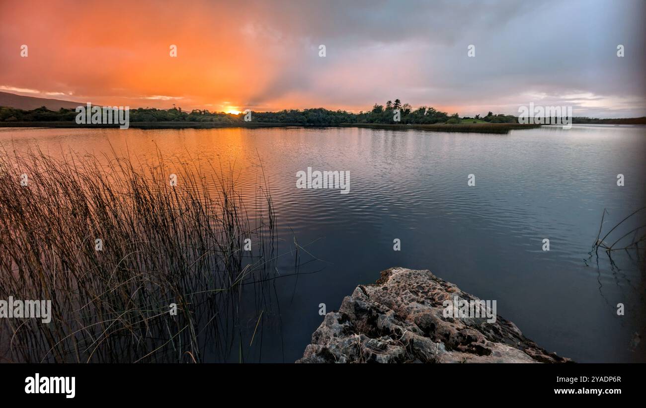 Splendido tramonto arancione sul lago, paesaggio a Ballyquirke lough, Galway, Irlanda, sfondo naturale Foto Stock