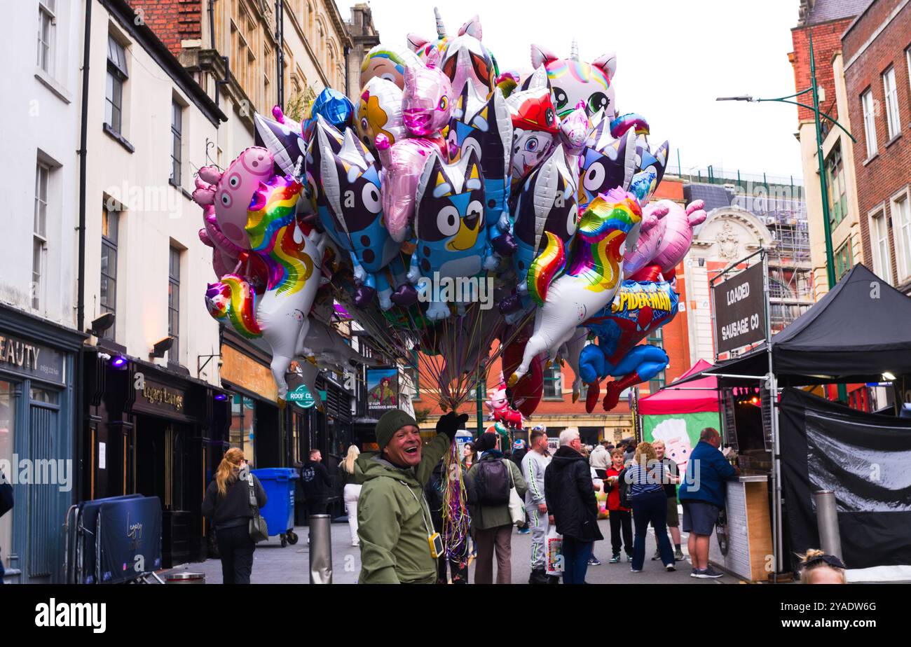 Palloncini colorati in vendita da un venditore felice, al festival del cibo di Newports. Ottobre 2024. Galles del Sud. Foto Stock