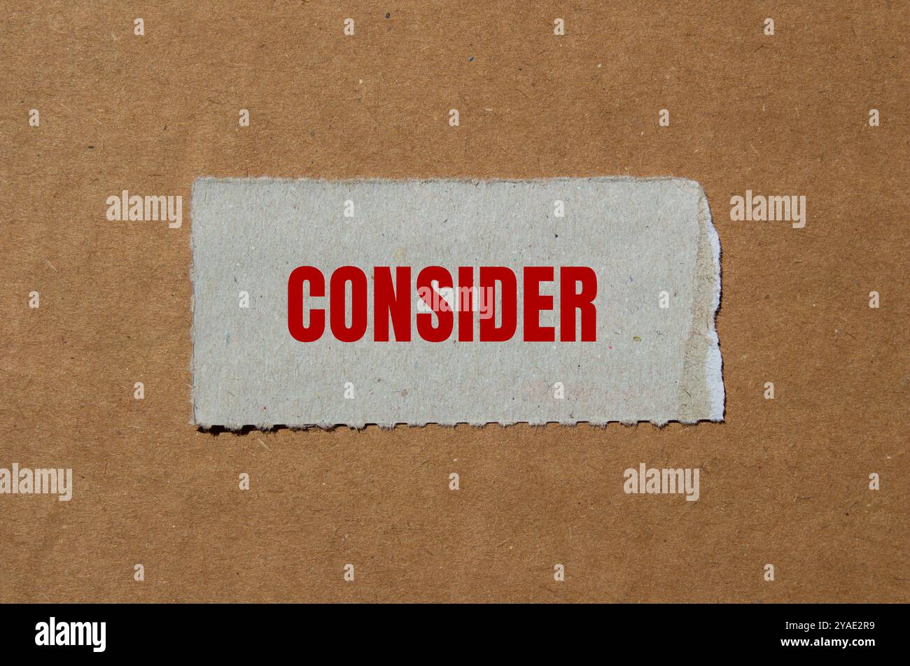 Considerare il messaggio scritto su un pezzo di carta strappato con sfondo di cartone. Simbolo concettuale da considerare. Copia spazio. Foto Stock