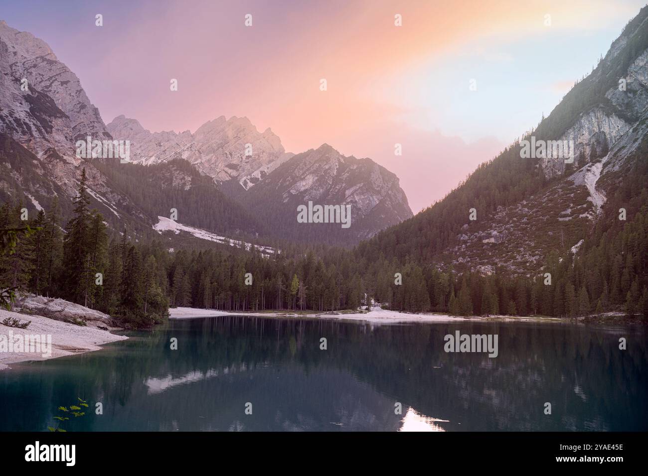 Serena serata estiva al Pragser Wildsee con maestose riflessioni sulle cime dolomitiche, lussureggianti pinete e il Lago di Smeraldo, in alto Adige Foto Stock