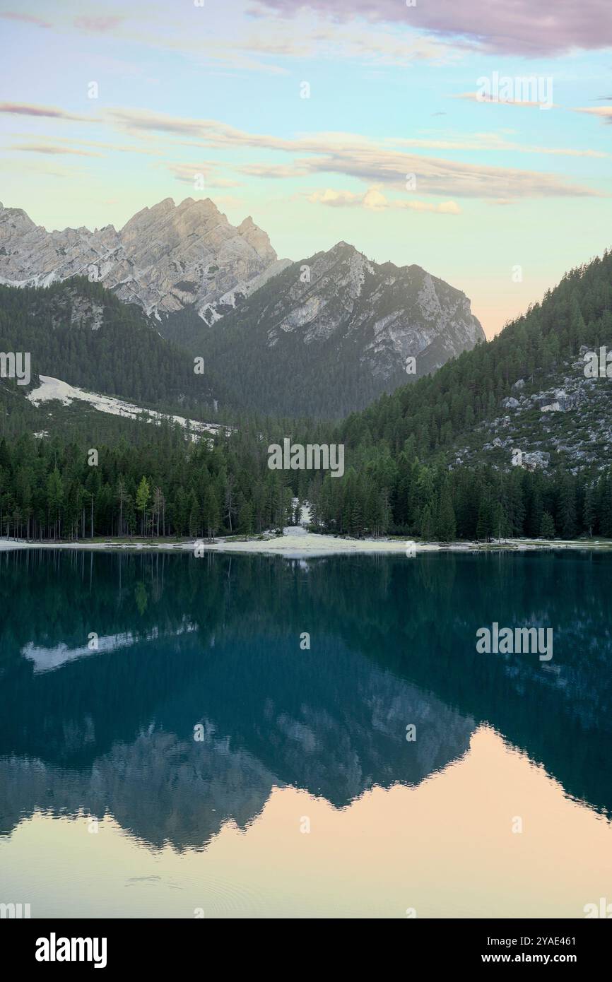 Serena serata estiva al Pragser Wildsee con maestose riflessioni sulle cime dolomitiche, lussureggianti pinete e il Lago di Smeraldo, in alto Adige Foto Stock