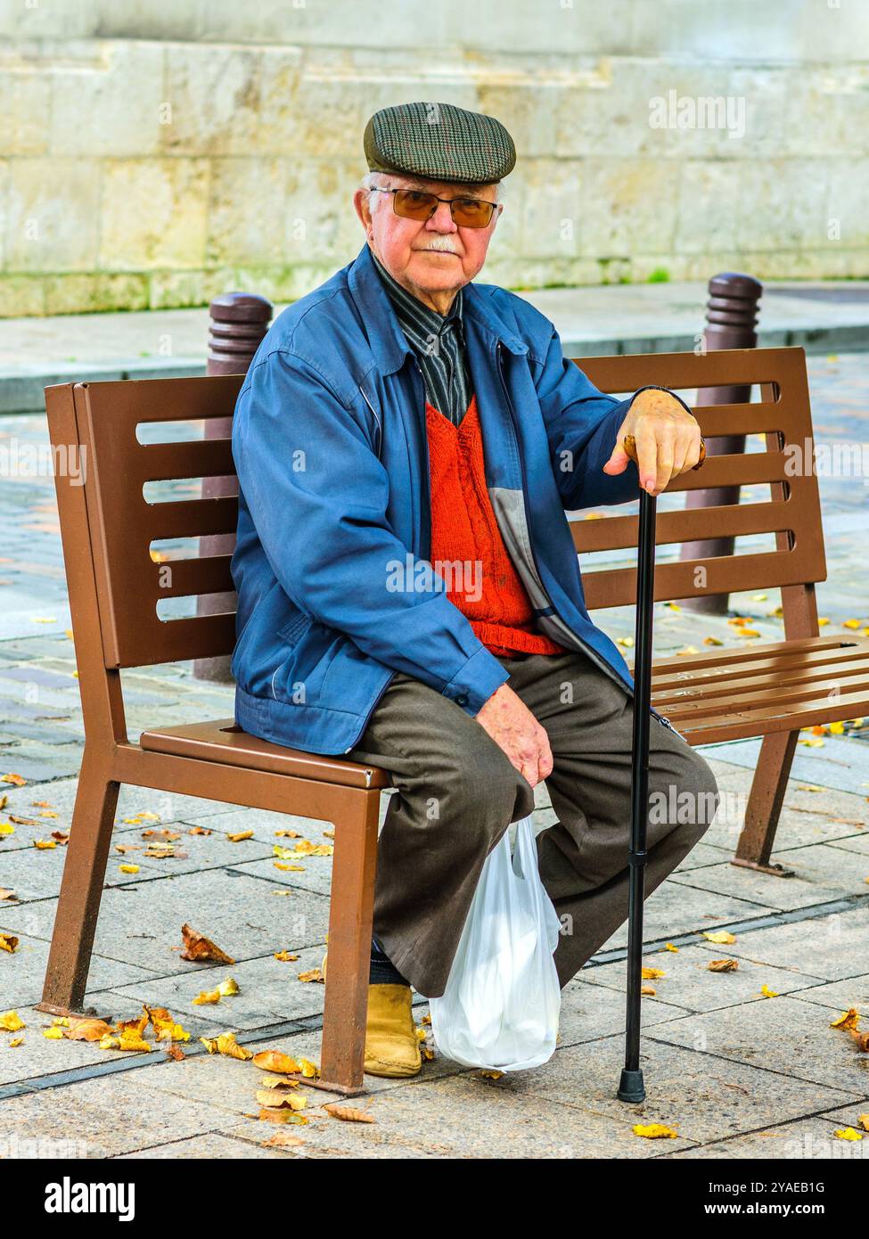 Uomo anziano con canna seduto su panchina di legno - Loches, Indre-et-Loire (37), Francia. Foto Stock