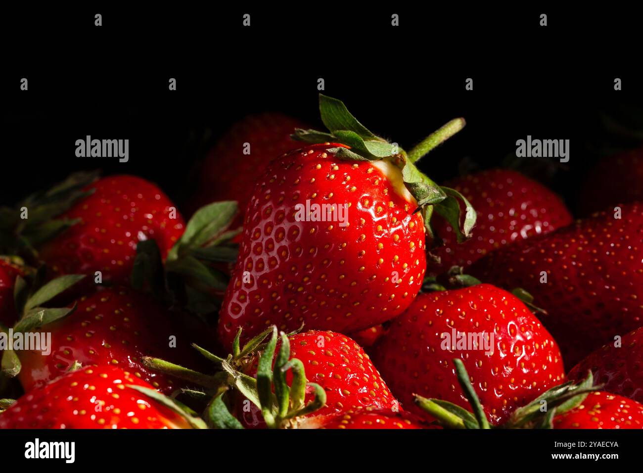 le fragole si accumulano su sfondo nero Foto Stock