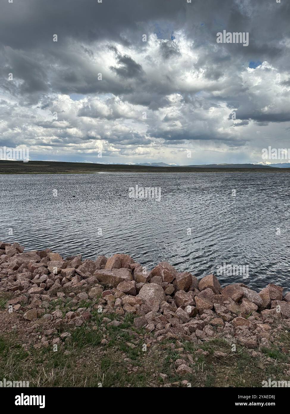 Un lago in una giornata ventosa con montagne dietro di esso - Immagine stock catturata con smartphone