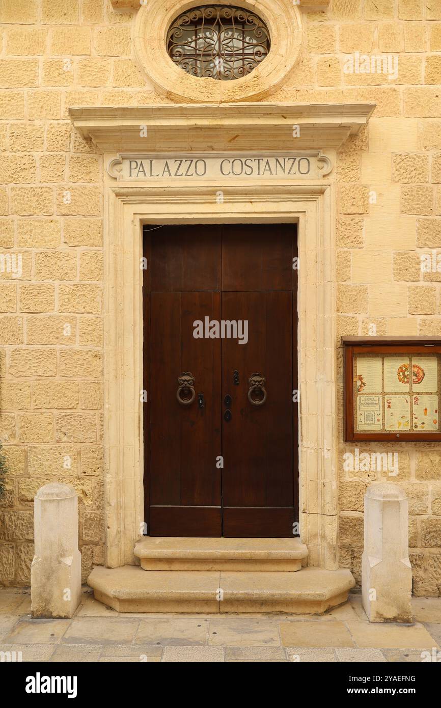 Dunkelbraune Holztür. Türklopfer. Verzierung. Rundes Fenster. Kalkstein. antik. Mdina. Malta. porta in legno marrone scuro. bussano alla porta. ornamento. antico Foto Stock