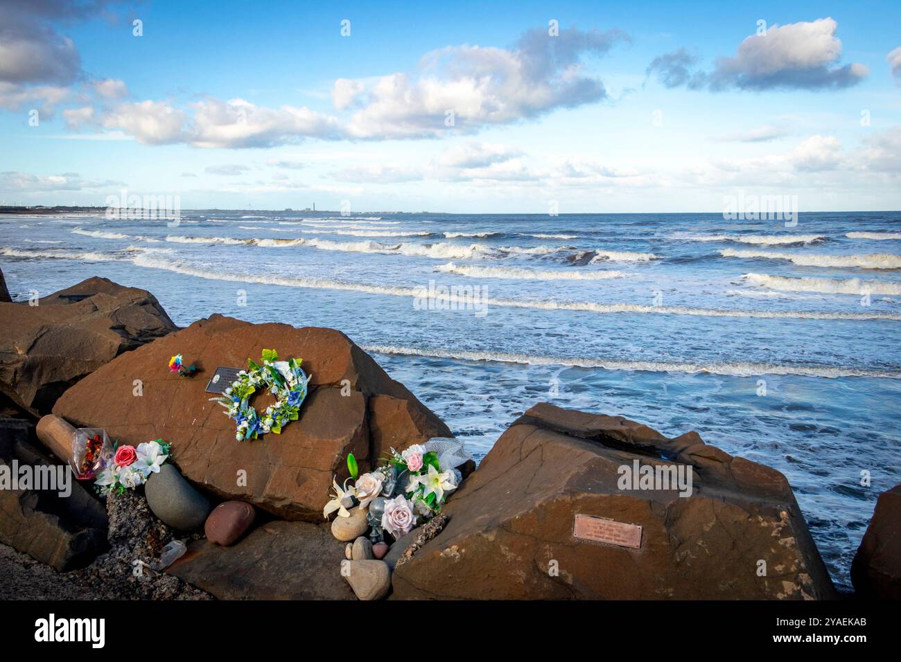 tributi floreali sulla costa rocciosa e onde infranti sulla spiaggia di cambois vicino a blyth northumberland Foto Stock