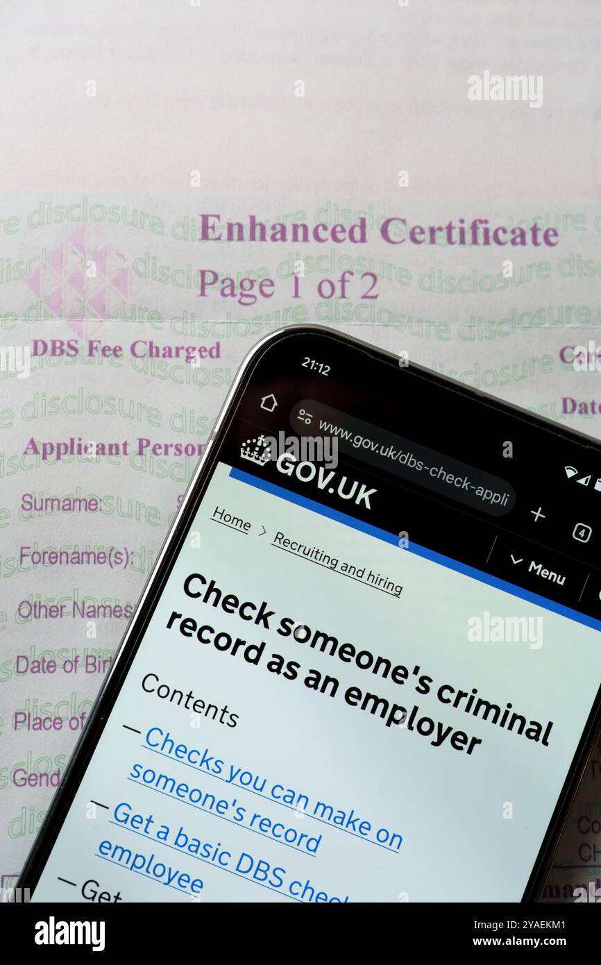 Sito Web governativo del Regno Unito su dispositivo mobile accanto al certificato DBS Enhanced per controllare i precedenti penali di qualcuno online. Stafford, Regno Unito, Augus Foto Stock
