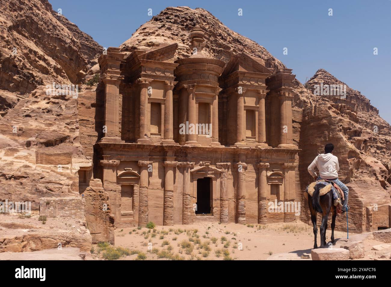 Ragazzo su un cavallo che ammira le rovine di Petra, in Giordania Foto Stock