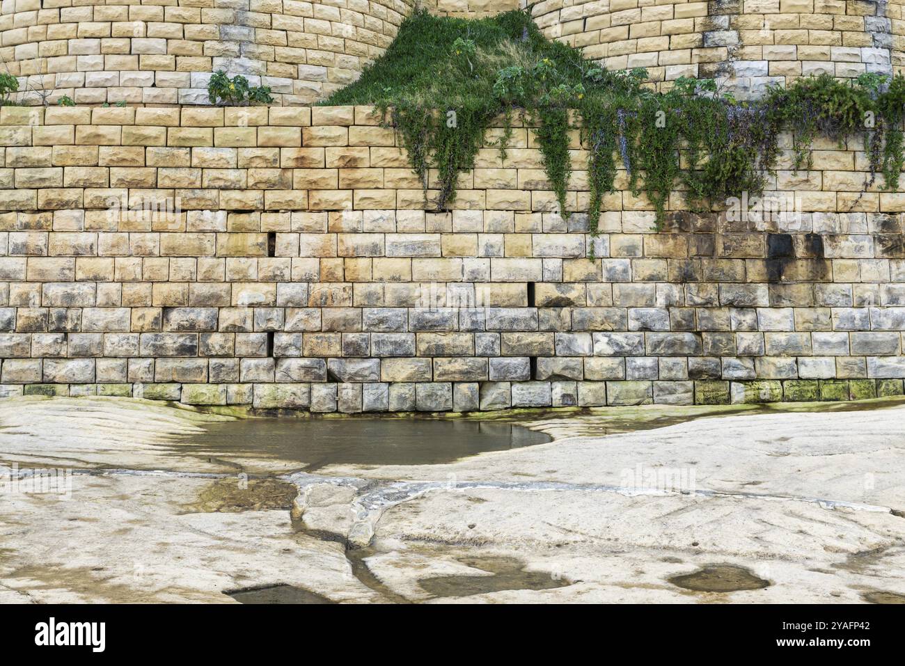 Muro di pietra marrone indossato sulla spiaggia di Saint Julian Bay, Malta, Europa Foto Stock