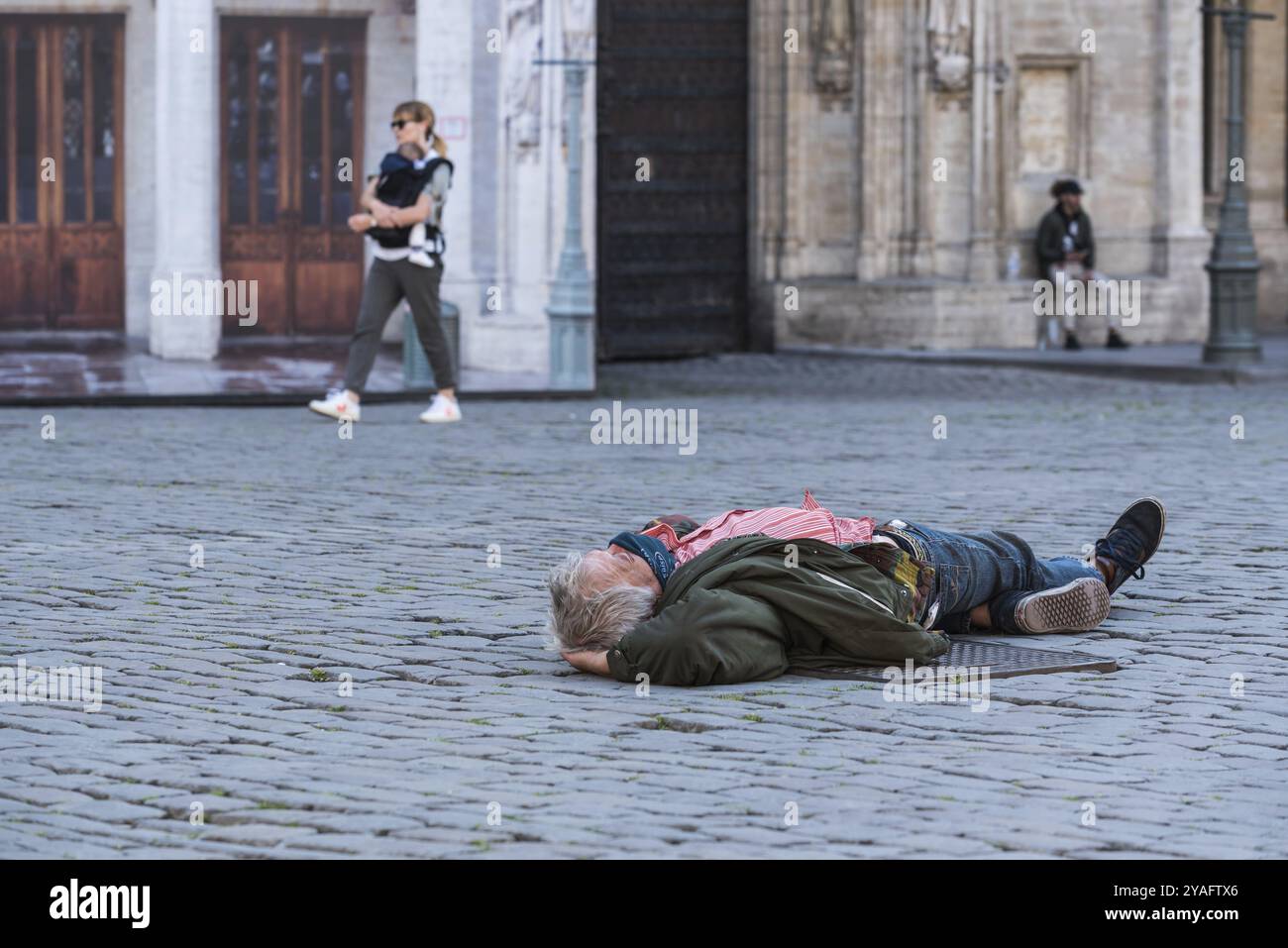 Città vecchia di Bruxelles, regione di Bruxelles capitale, Belgio, 05 18 2020 uomo anziano adagiato sulle pietre di ciottoli della Grand Place di Bruxelles, Europa Foto Stock