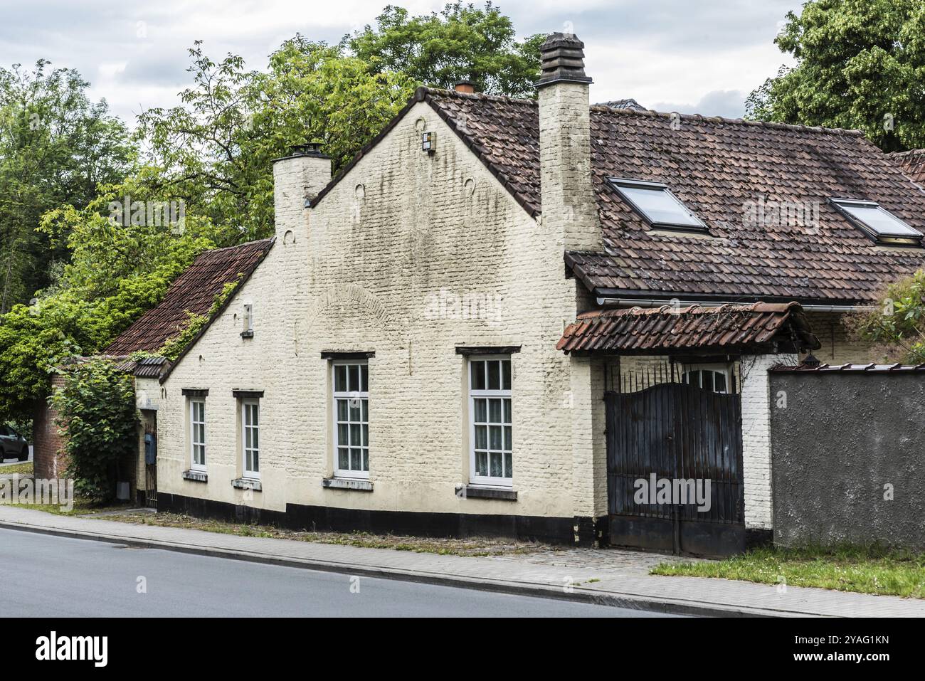 Uccle, Bruxelles, Belgio, 06 14 2019 facciata di una vecchia casa contadina e porta in città su una strada deserta, Europa Foto Stock