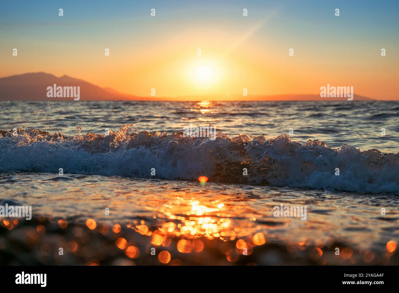 Le onde del Mar Egeo si schiantano sulla spiaggia sabbiosa di Vrasna, Grecia. Messa a fuoco selettiva. Foto Stock