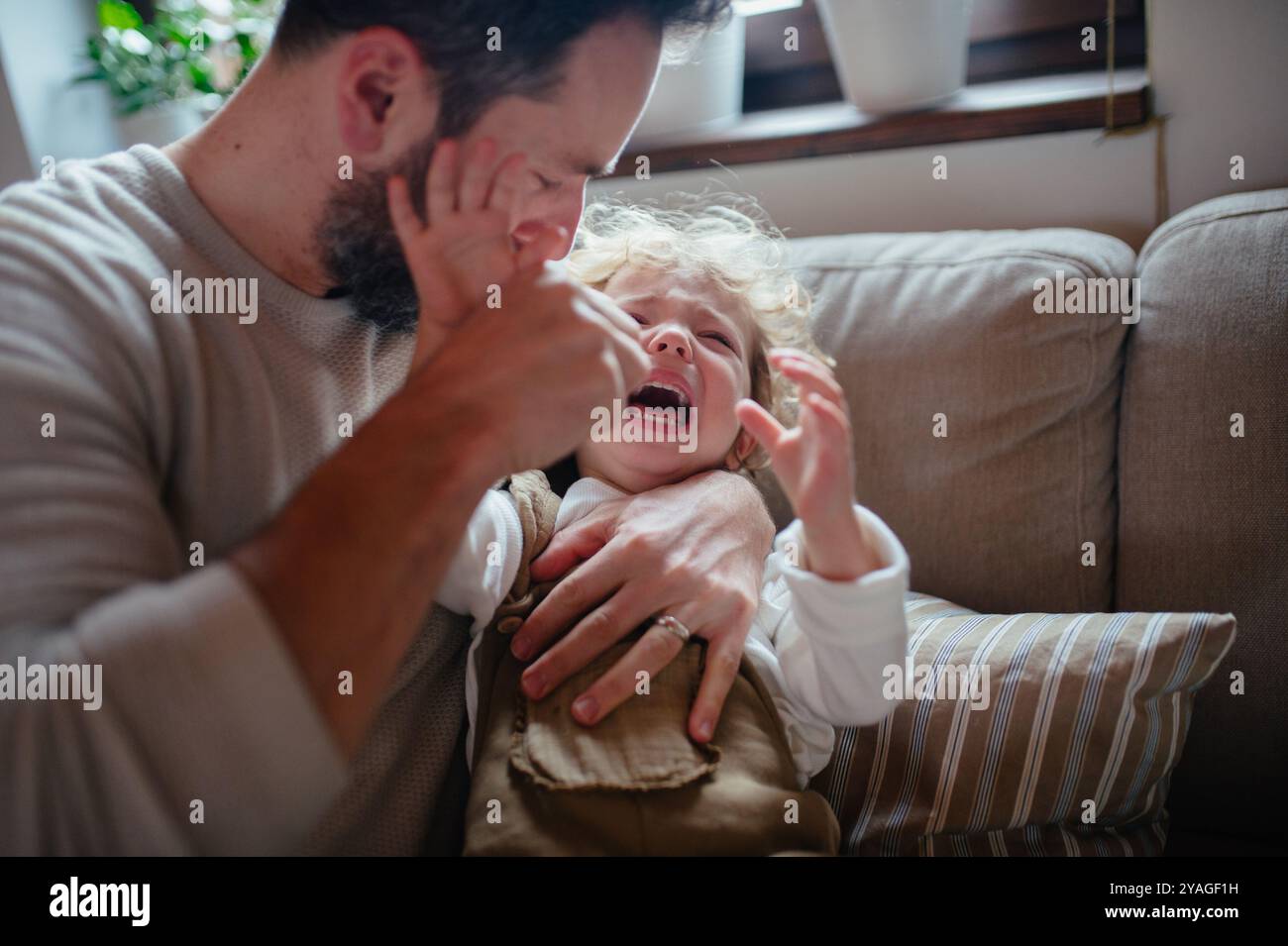 Ragazza malata con febbre e freddo a casa. Padre che ha una figlia che piange. Foto Stock