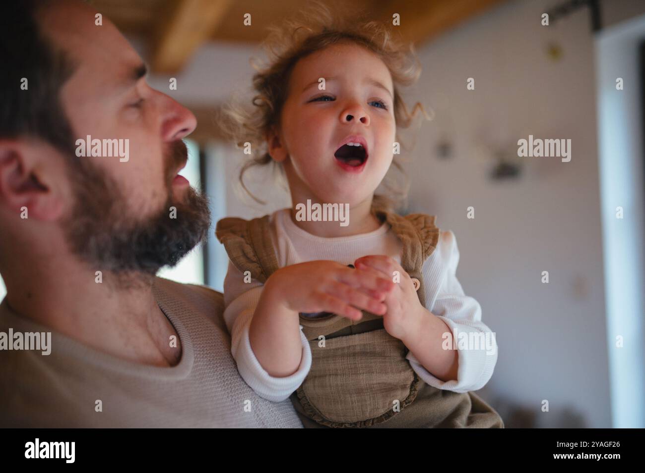 Ragazza malata con febbre e freddo a casa. Padre che ha una figlia che piange. Foto Stock