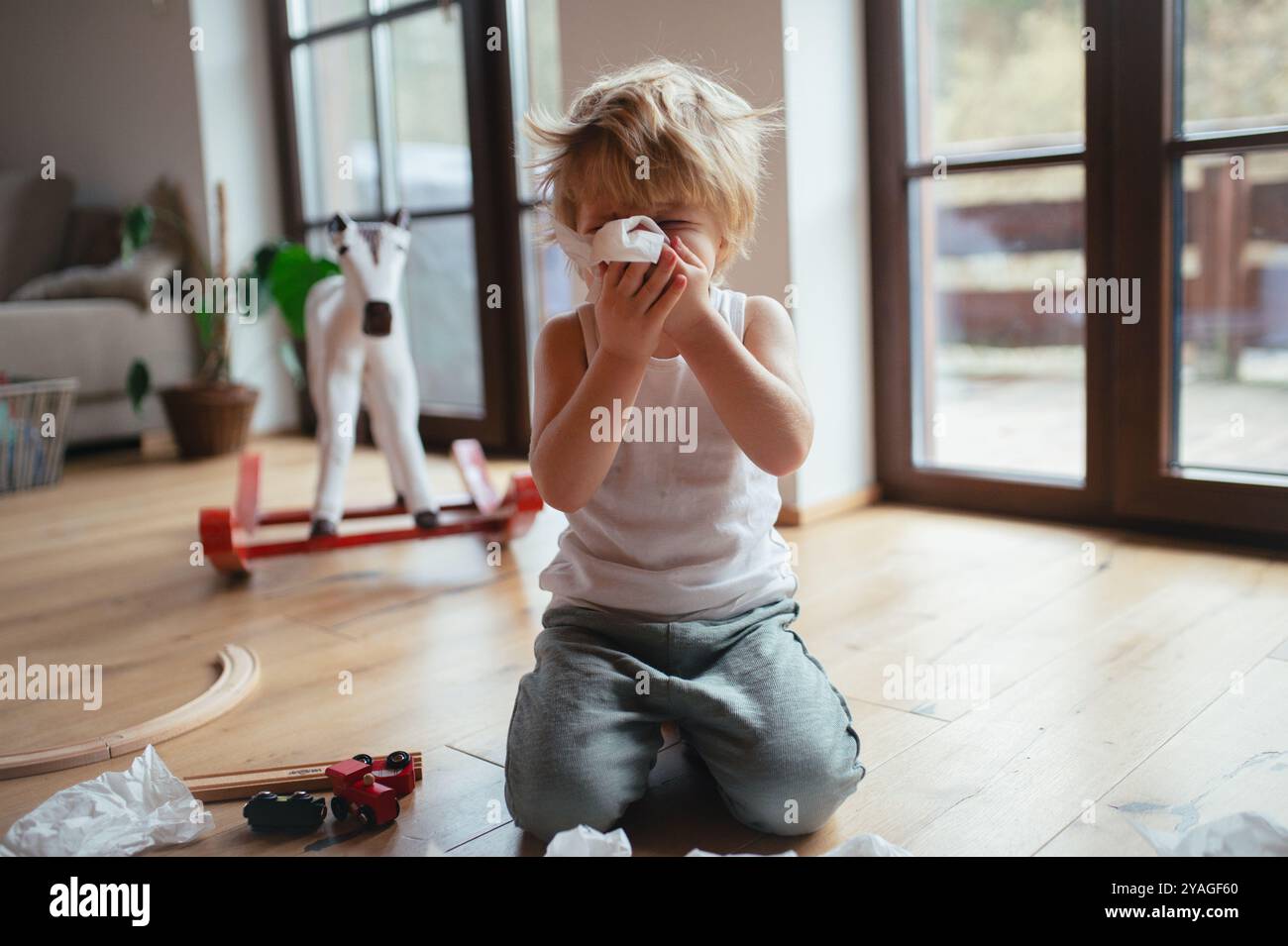 Il ragazzo malato con il freddo ha il naso soffocato e soffia il naso. Foto Stock