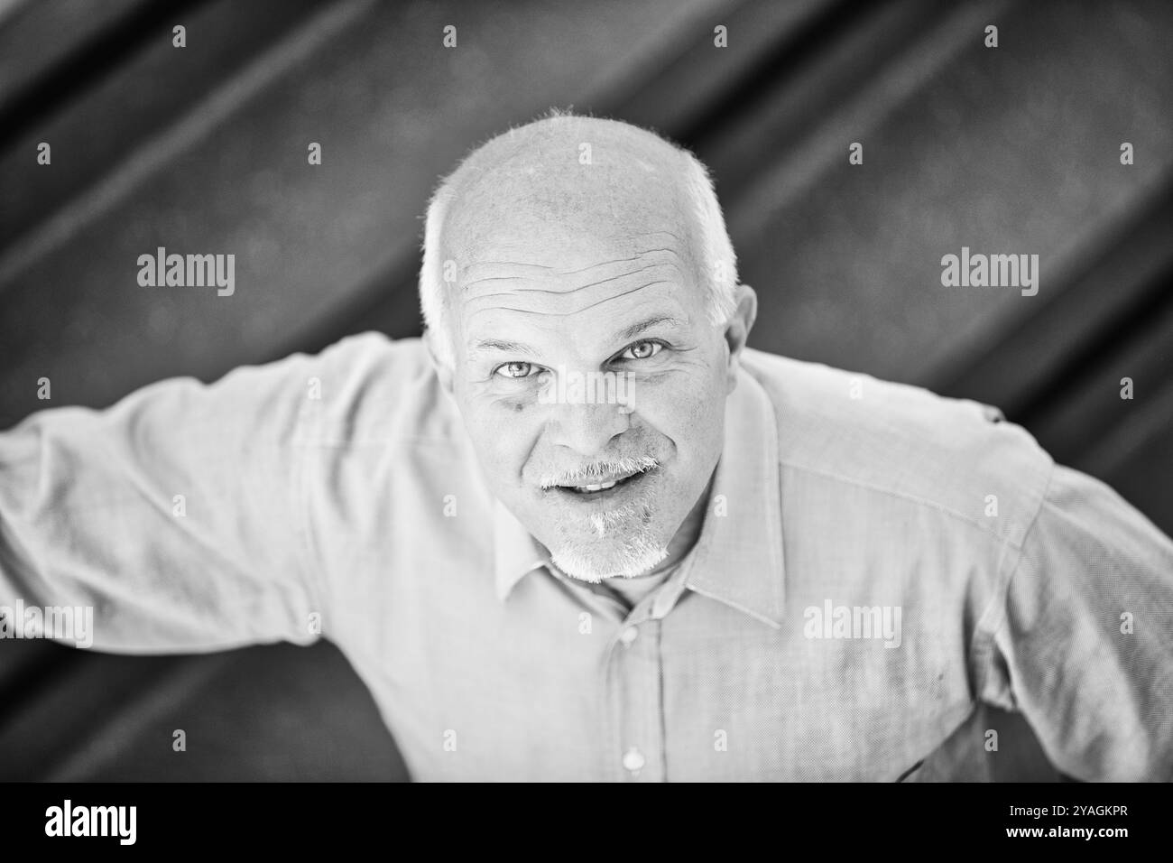 Un senior manager sorridente si pone con sicurezza in un ufficio moderno. Questo ritratto in bianco e nero cattura la sua carriera di successo Foto Stock