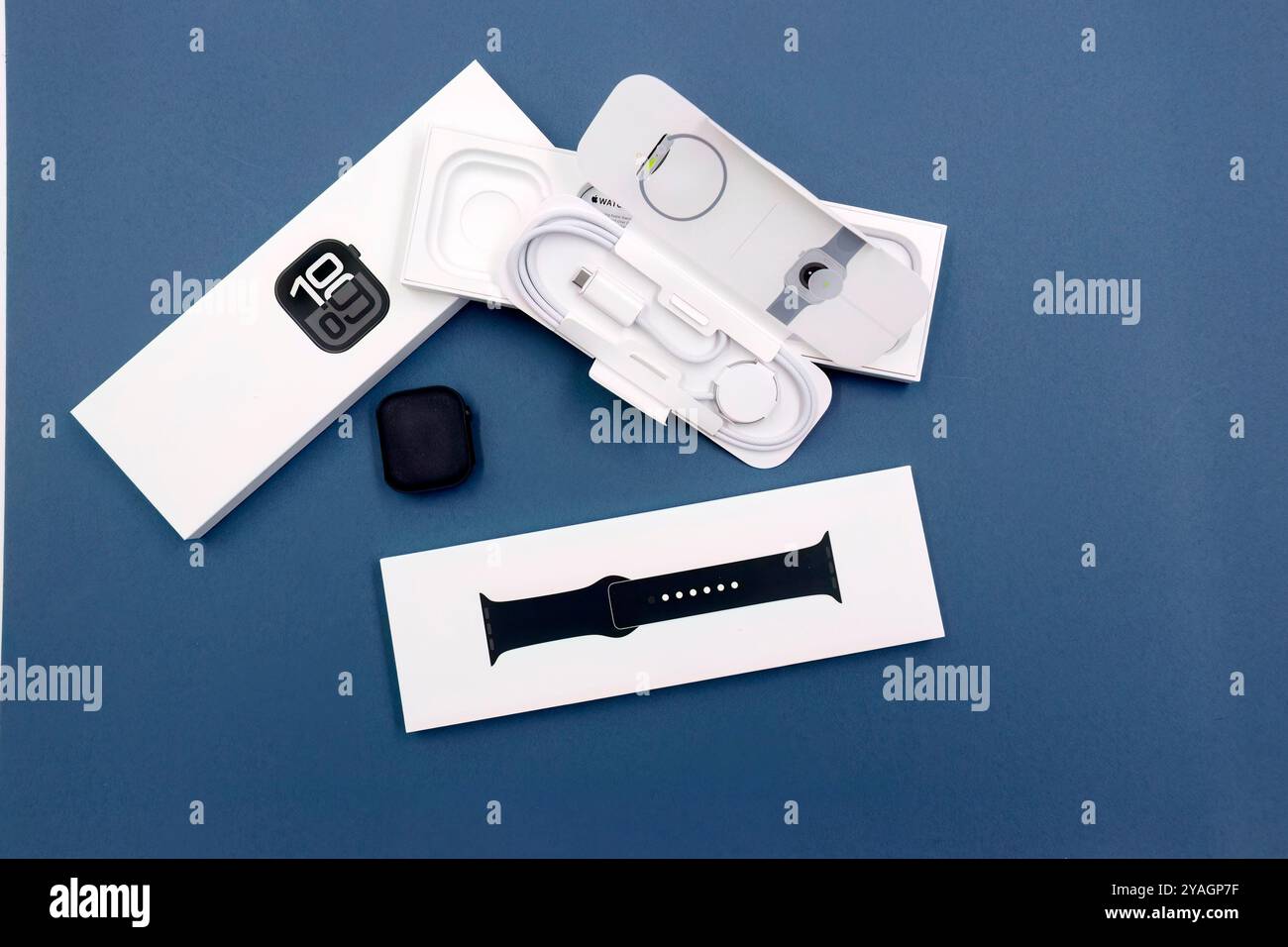 Confezione con la nuova configurazione dello smartwatch Apple Watch serie 10 del 2024, unboxing e braccialetto intercambiabile su sfondo blu Design elegante Foto Stock