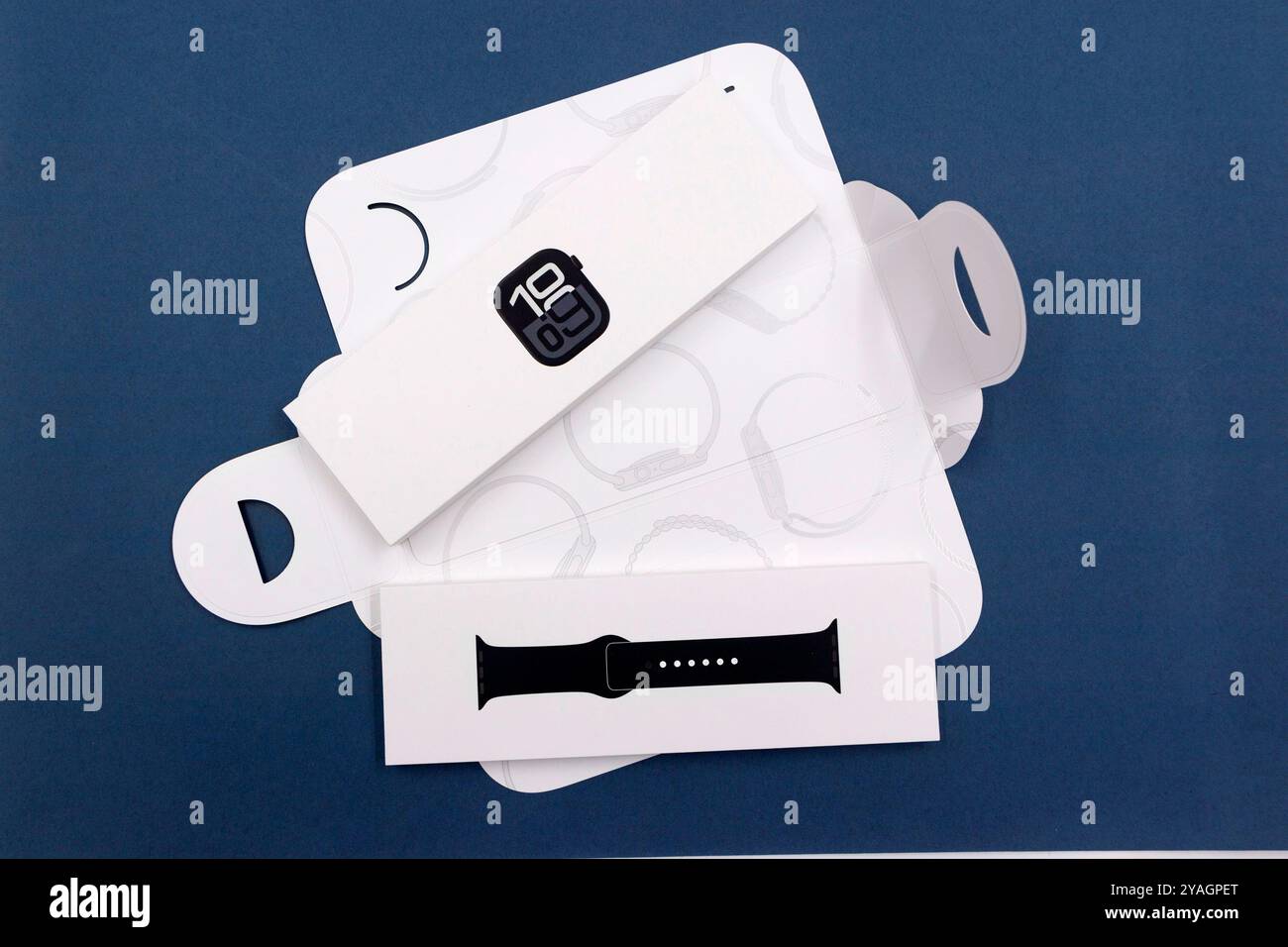 Confezione con la nuova configurazione dello smartwatch Apple Watch serie 10 del 2024, unboxing e braccialetto intercambiabile su sfondo blu Design elegante Foto Stock