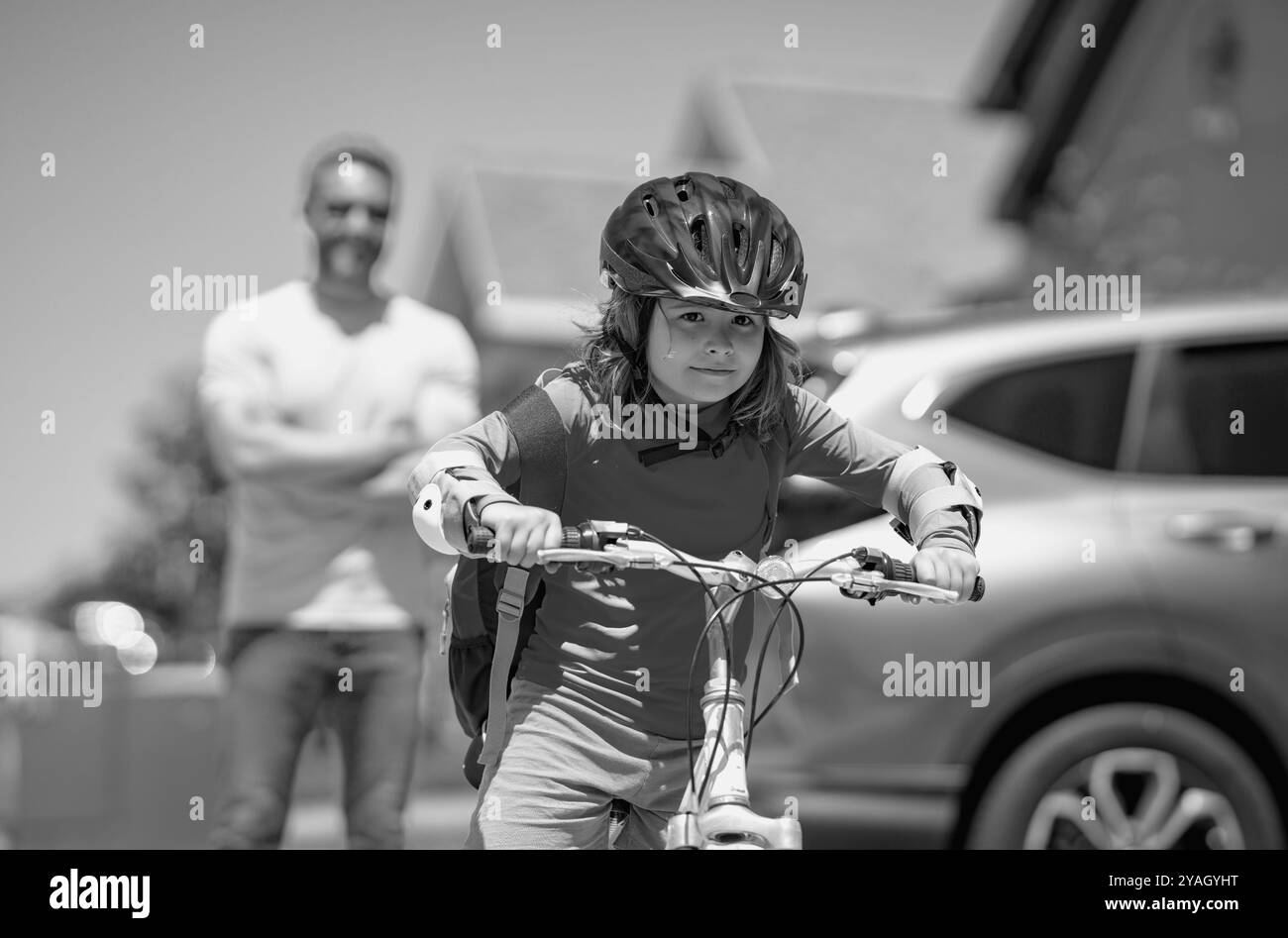 Padre e figlio in bicicletta. Padre e figlio in bicicletta nel parco estivo. Bambini imparano a andare in bicicletta. Padre e figlio che indossano biciclette Foto Stock