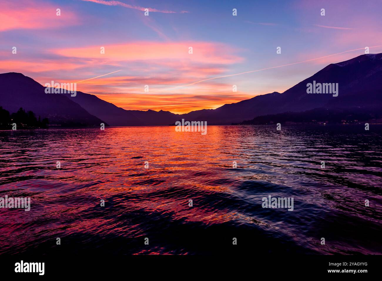 Tramonto sul Lago di Como con montagne nella nebbia in una giornata invernale Bellagio Como Lombardia Italia Foto Stock