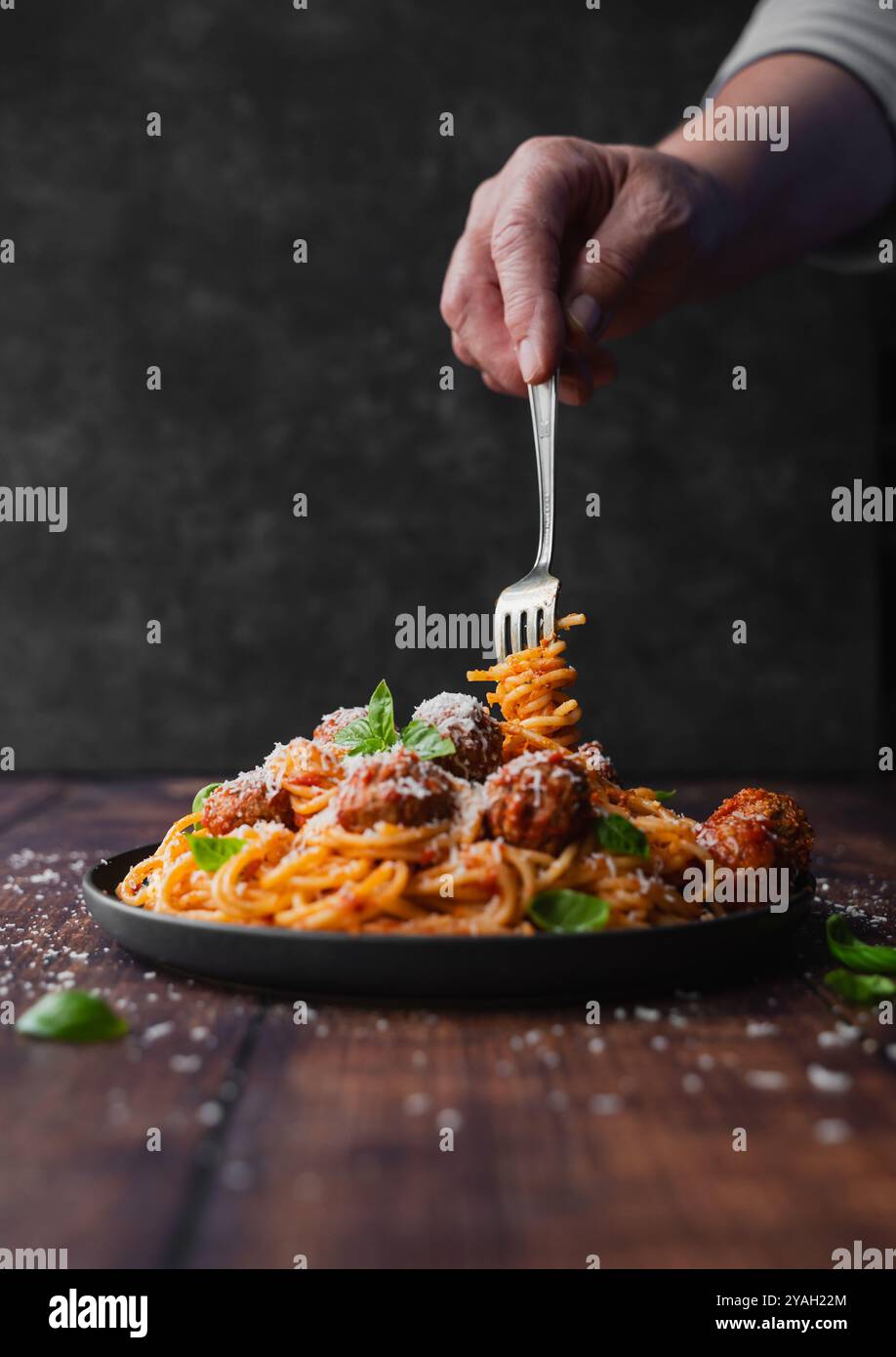 Forchetta girevole a mano in piatto di spaghetti e polpette sul tavolo. Foto Stock