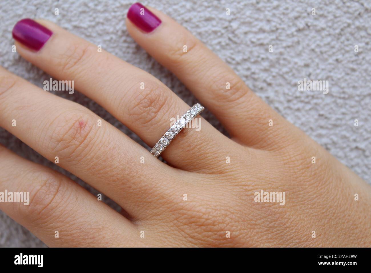 Anello di diamante su una bella mano e sfondo di un muro Foto Stock