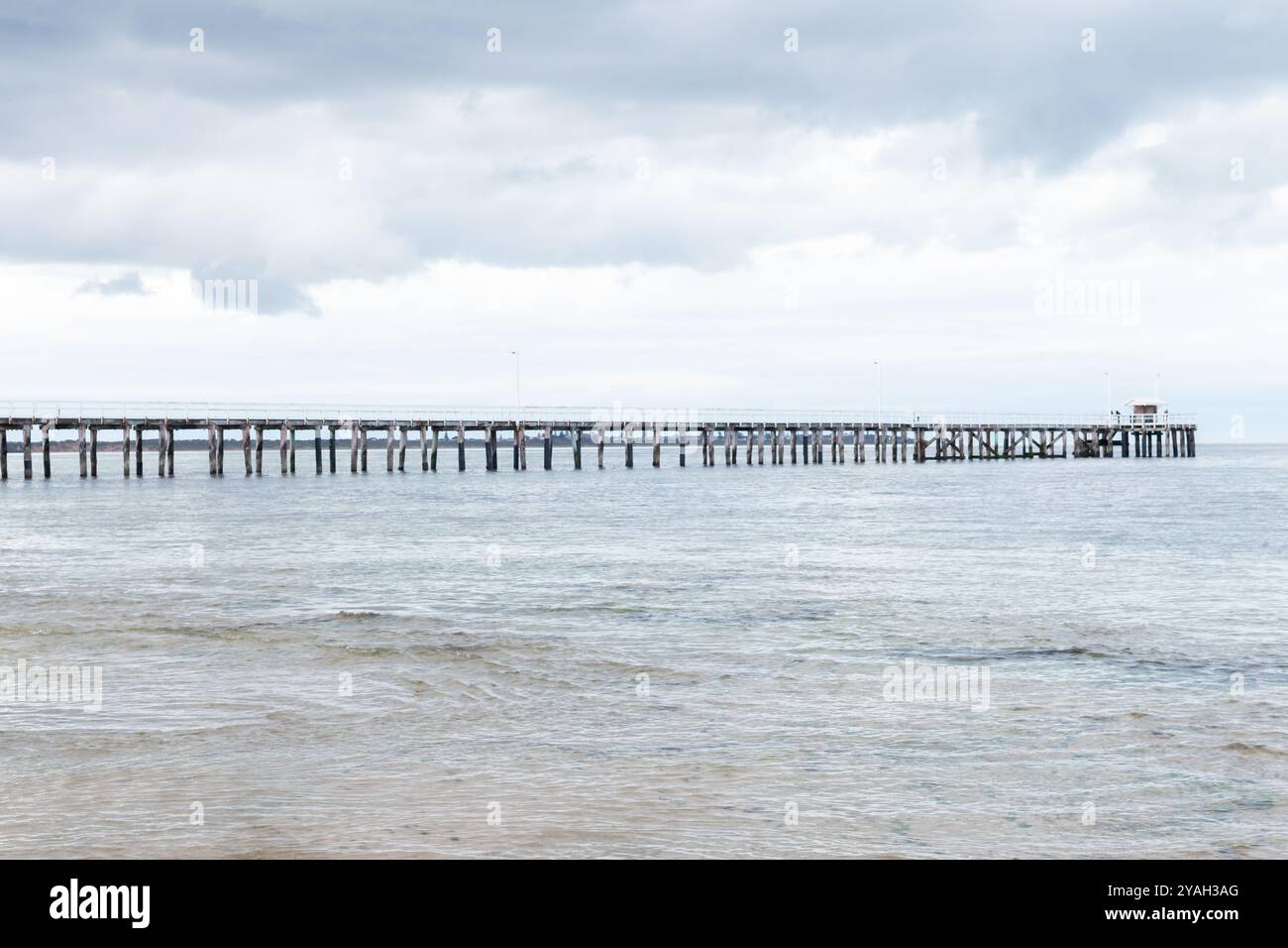 Il molo di Point Lonsdale si estende nell'oceano, sotto un cielo soffice coperto Foto Stock